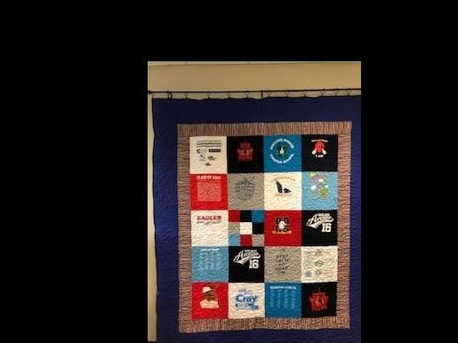 Colorful quilt made of past OACS t-shirts on display in front office. 