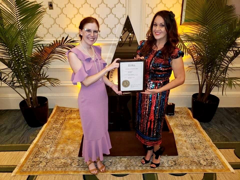 Two women posing with an award