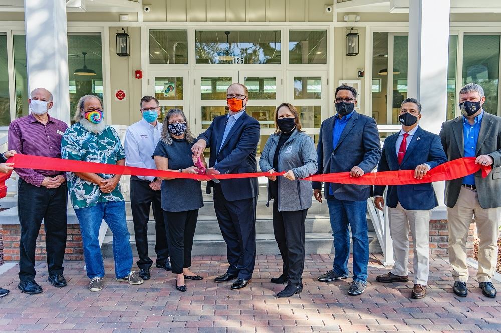 A group of people cutting a red ribbon